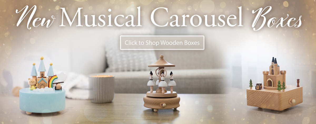 Text "New Musical Carousel Boxes, Click to shop Wooden Boxes". Three Wind-up Carousels on counter of home.